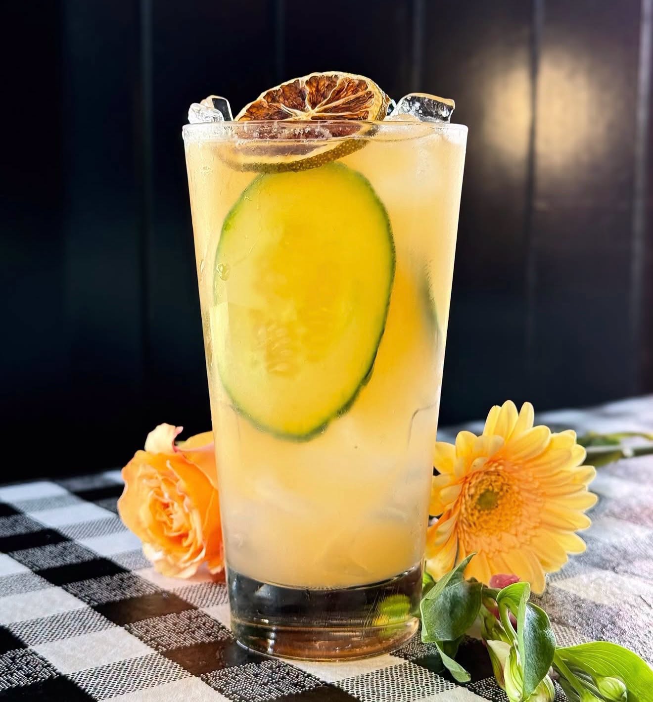 A citrus and cucumber cocktail garnished with dried lime at the bar