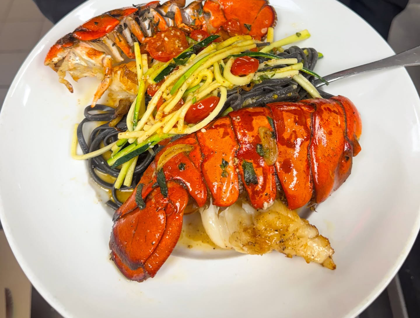 Lobster tails over squid-ink pasta with garden vegetables